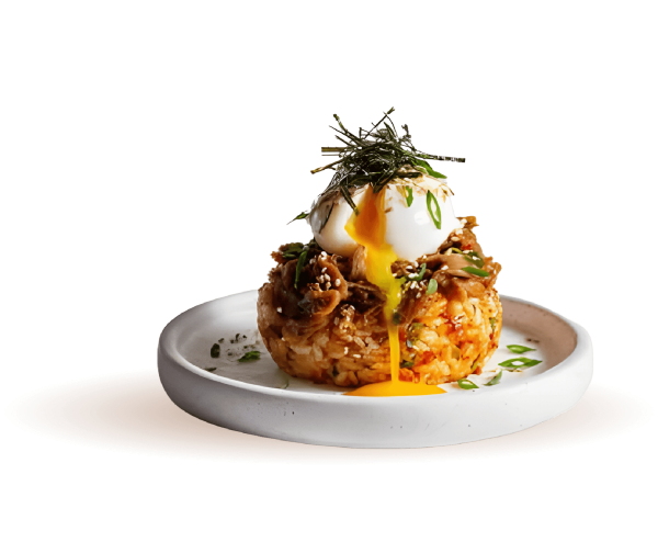 A beautifully plated gourmet dish from the Mozaic catering menu, featuring a seasoned rice cake topped with shredded savory meat and a soft-poached egg with its yolk dripping down the side, garnished with sesame seeds, green onions, and shredded nori.